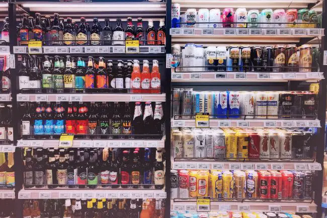 Stocked Store Shelves Of Bottled And Canned Beers.