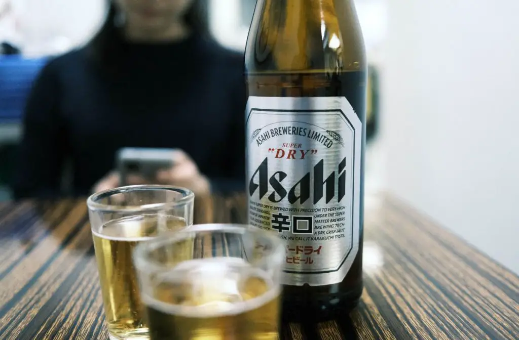 A Bottle And Glasses Filled With Asahi Super Dry.
